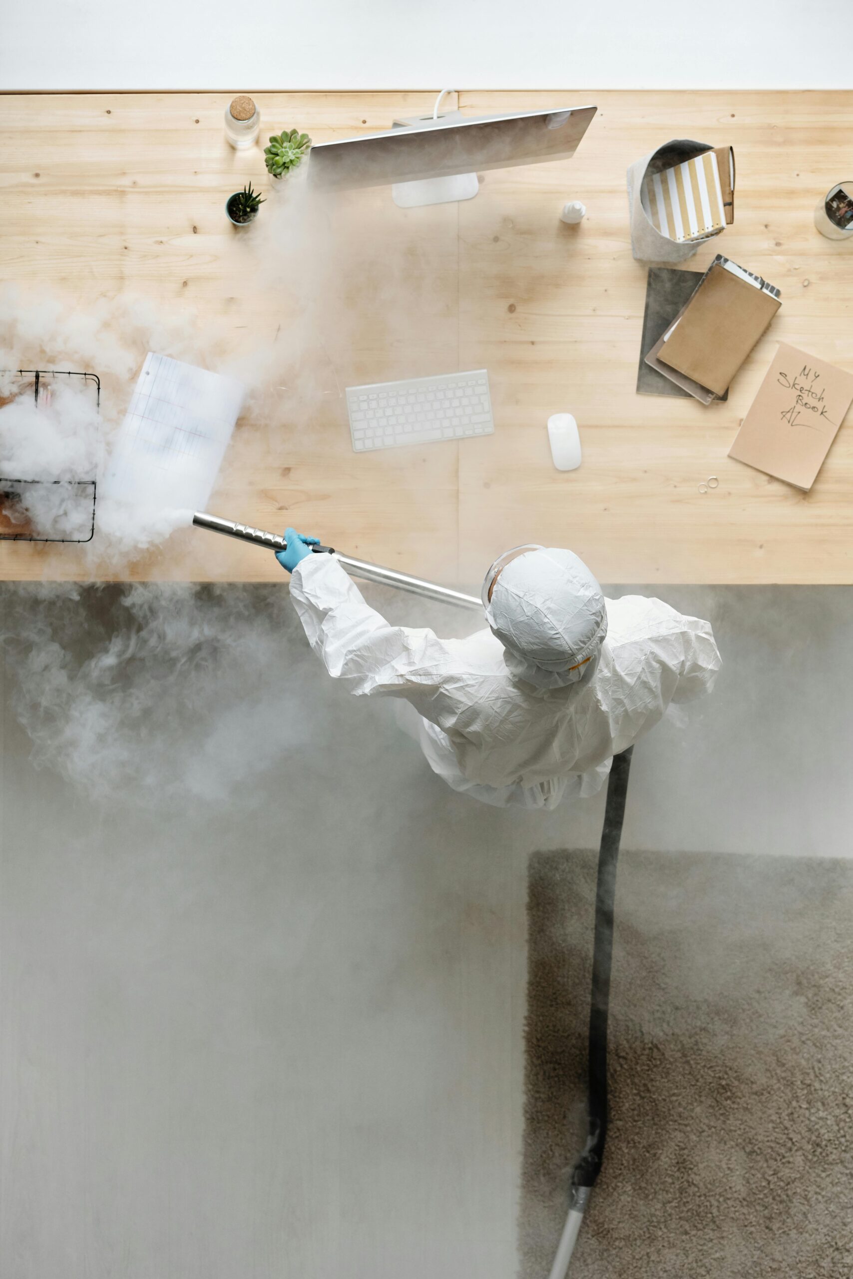 How Commercial Steam Cleaning Elevates Your Office Building in Atlanta & Marietta A person in PPE disinfects an office desk with steam, ensuring cleanliness and safety.